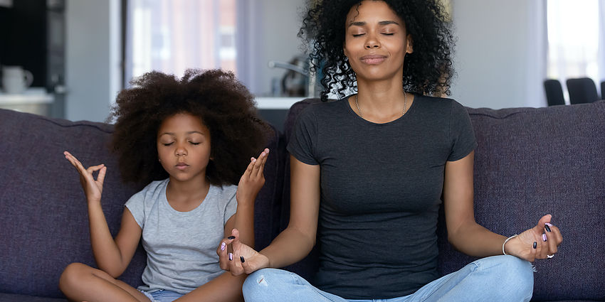 woman and girl sitting together meditating