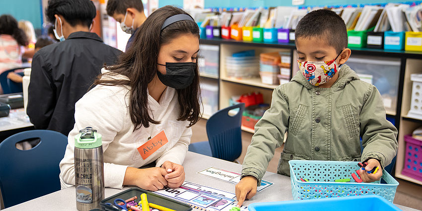 older student works with younger boy on spelling