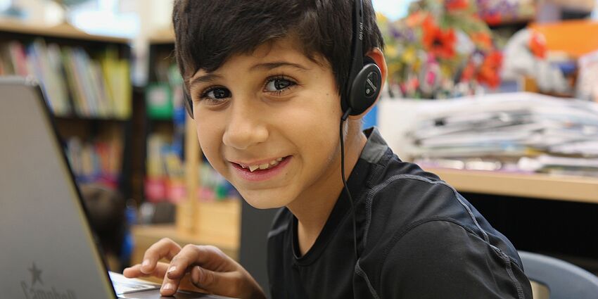 smiling boy with laptop and wearing headphones