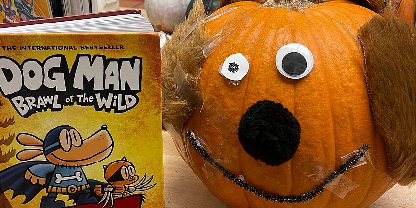 the book dog man brawl of the wild is displayed next to a pumpkin decorated like a dog 