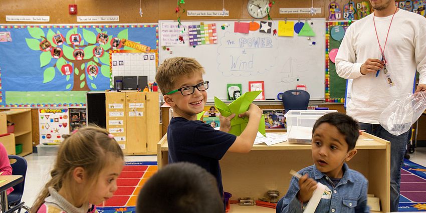 smiling boy shows the pinwheel he made