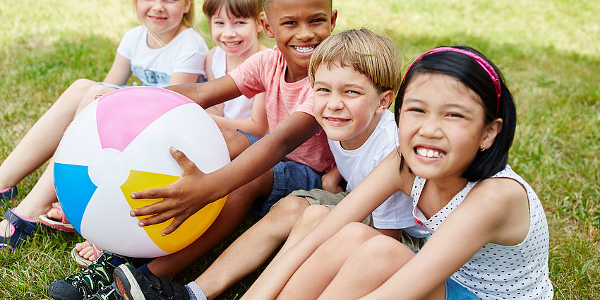 group of smiling children sitting on grass