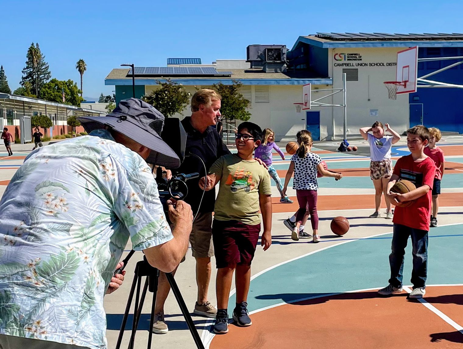 children on playground with cameraman and film director