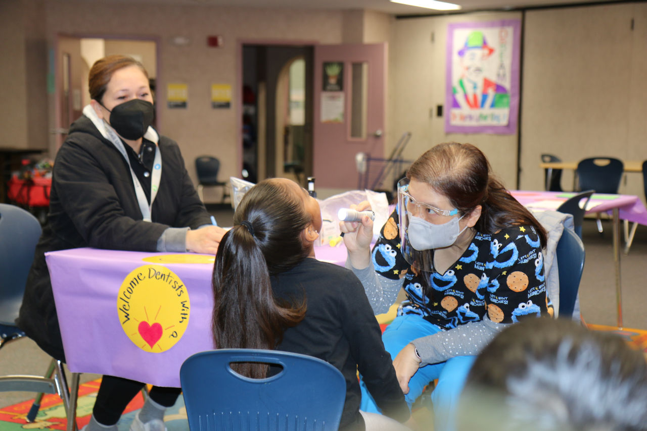 Woman looks on as dentist looks into a child's mouth