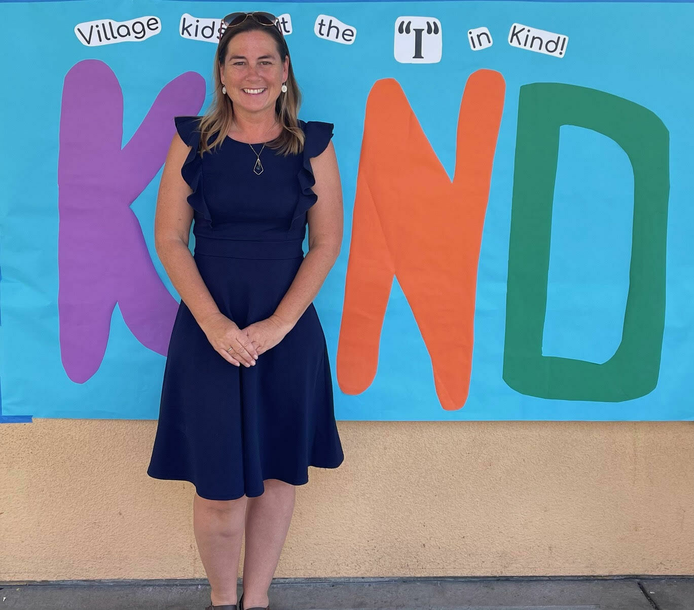 Principal standing infront of a colorful sign